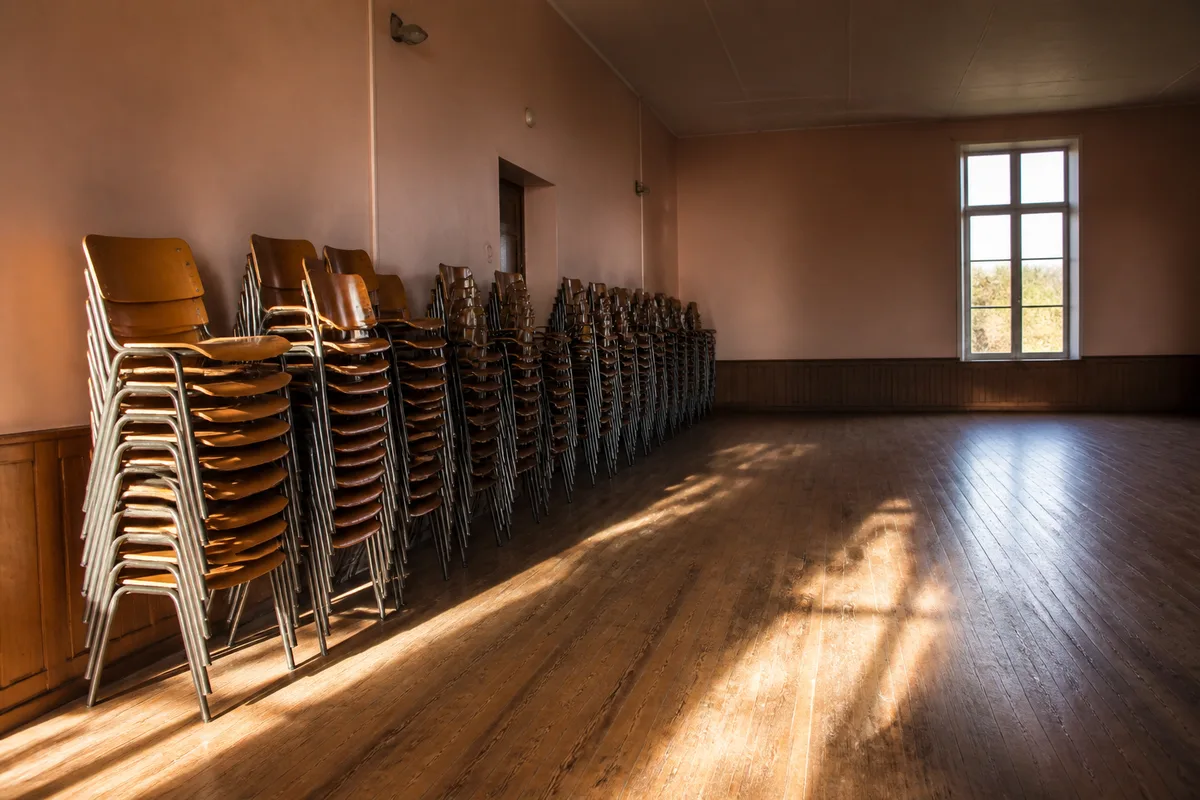 Chaises empilées le long d&rsquo;un mur dans une salle des fêtes de village